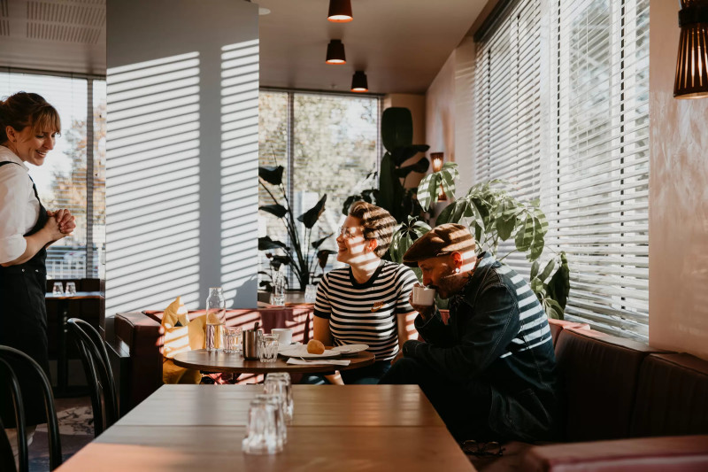 Interior shot of two people sitting at a table in Lagotto talking to a waitress